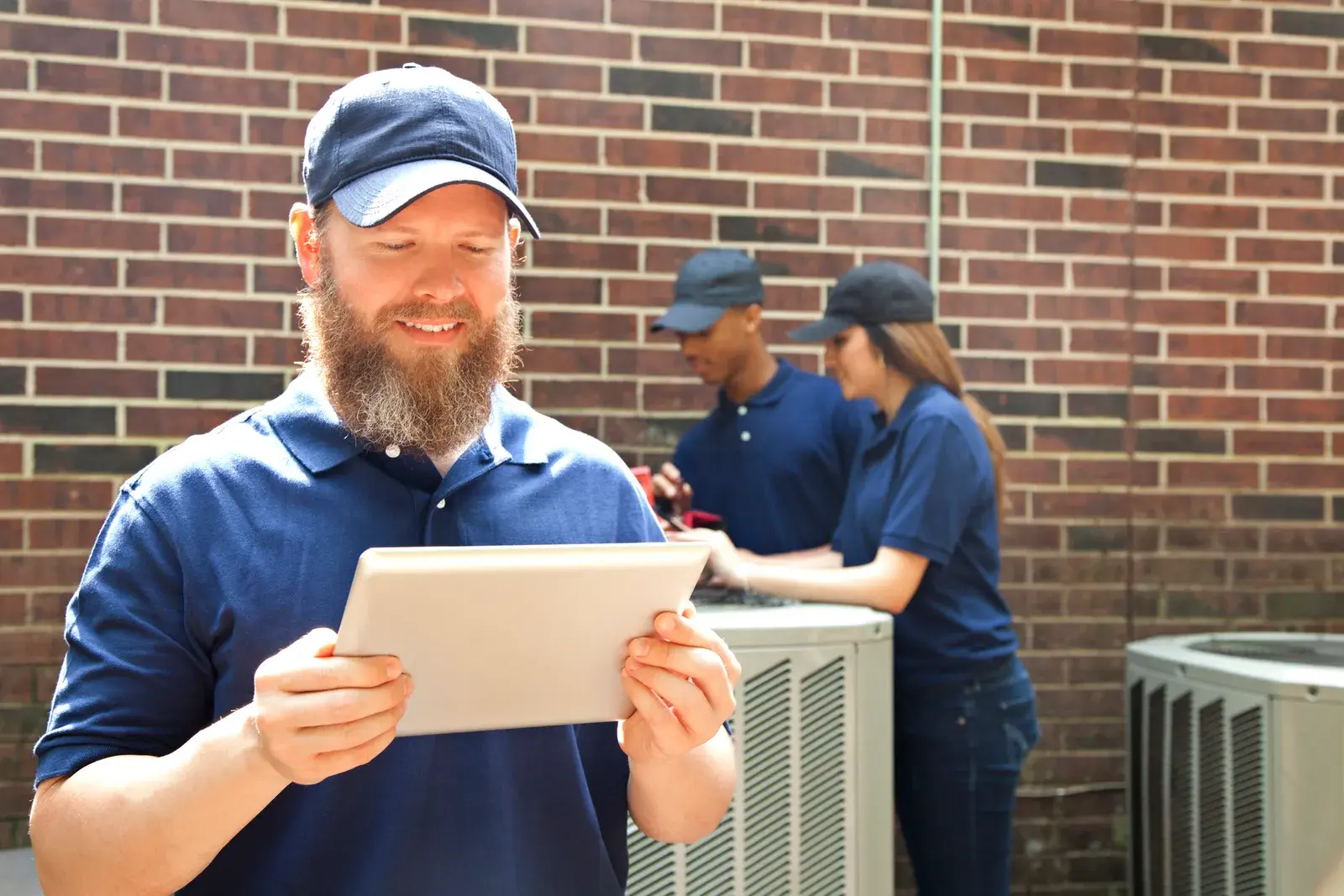 HVAC technicians reviewing a repair on a tablet beside an outdoor unit